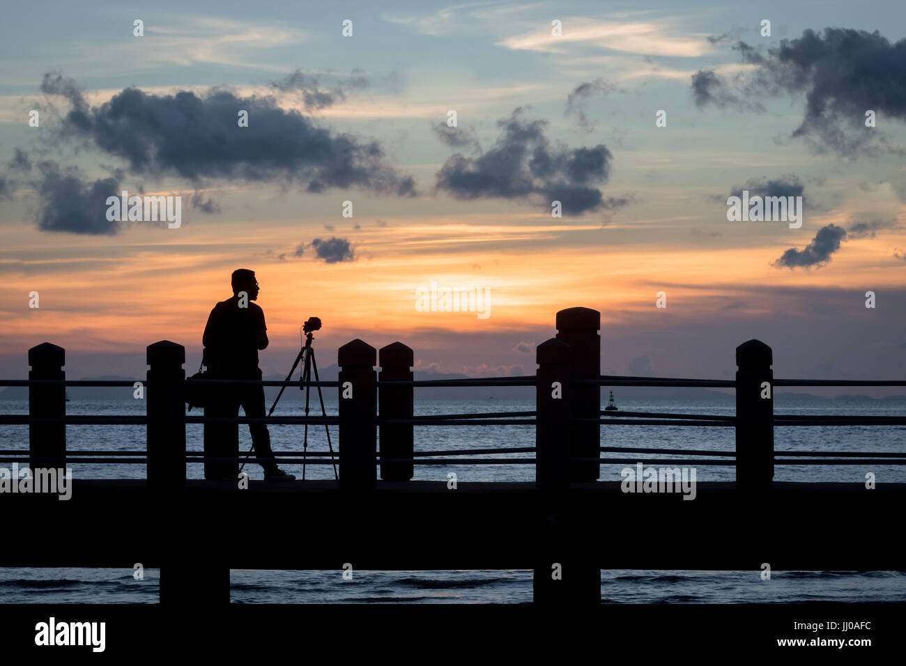 A photographer with camera fixed on a tripod in silhouette during ...