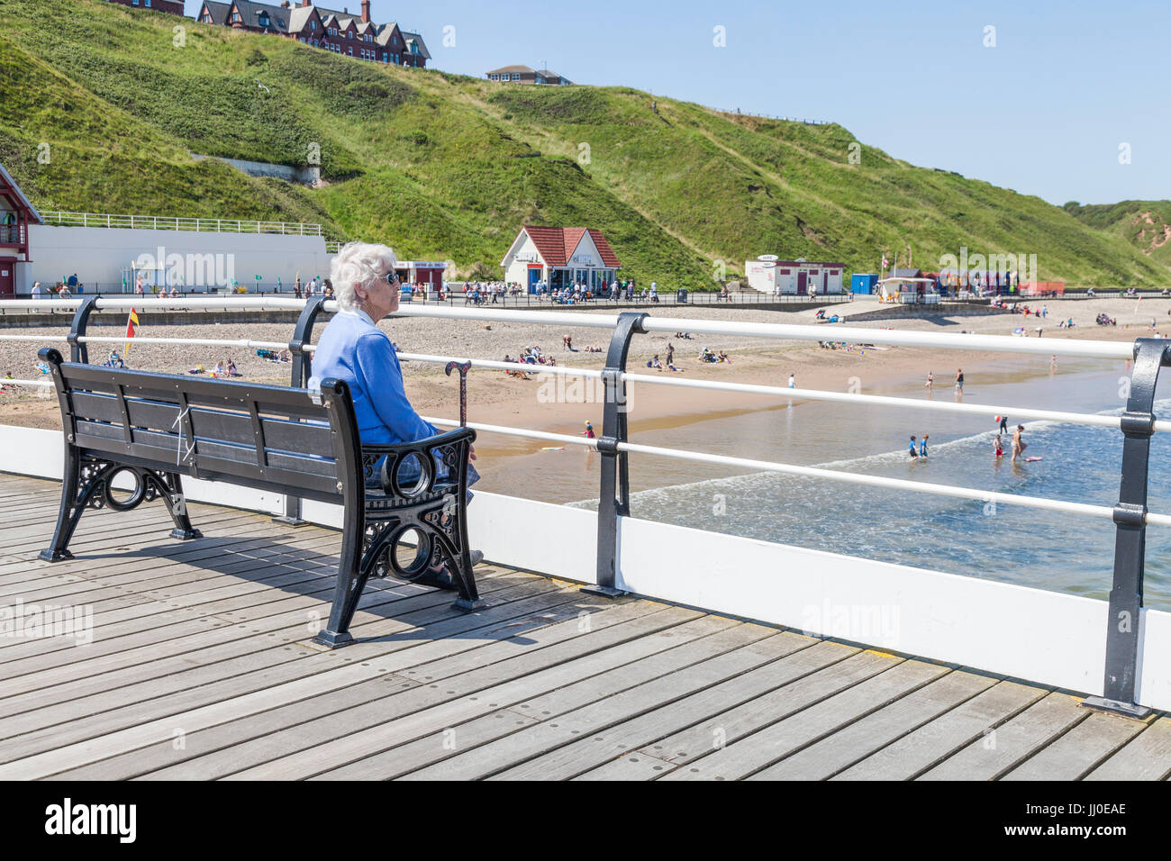 A Mature Woman Sat On A Bench By Herself Looking Out To Sea At Saltburn By The Sea England Uk