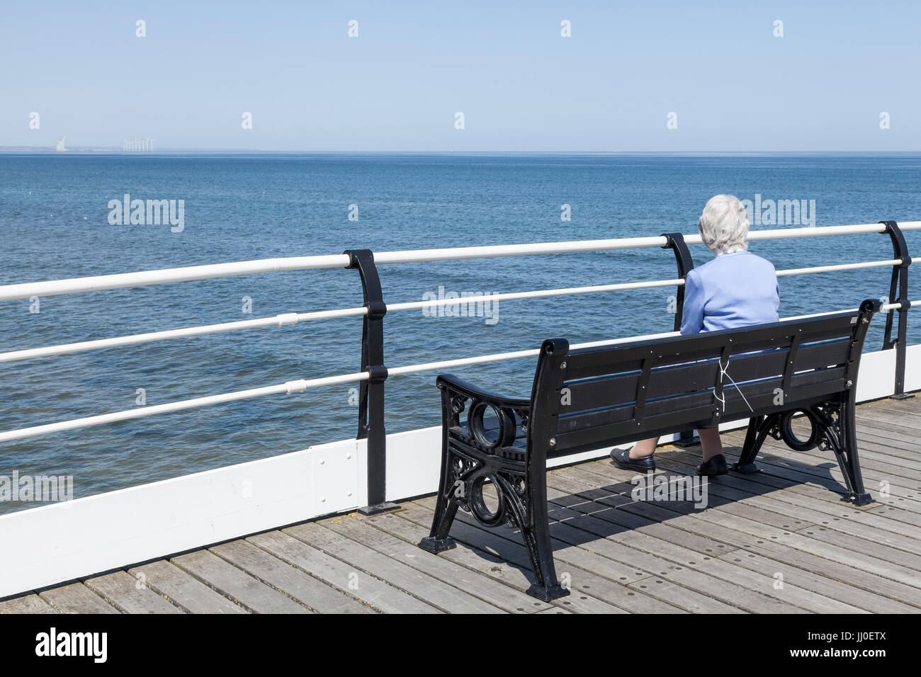 A Mature Woman Sat On A Bench By Herself Looking Out To Sea From The Pier At Saltburn By The Sea