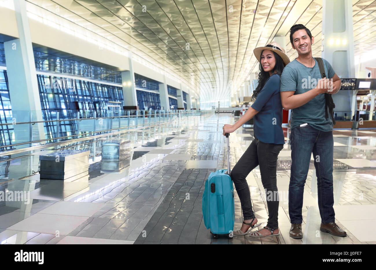 Young asian couple tourist with luggage waiting flight at airport terminal Stock Photo
