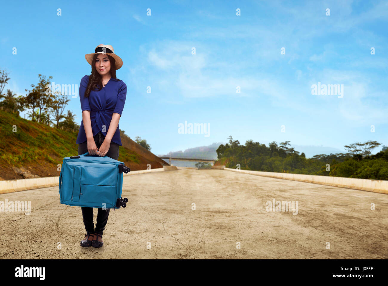 Pretty asian traveler with hat holding suitcase on the street Stock Photo