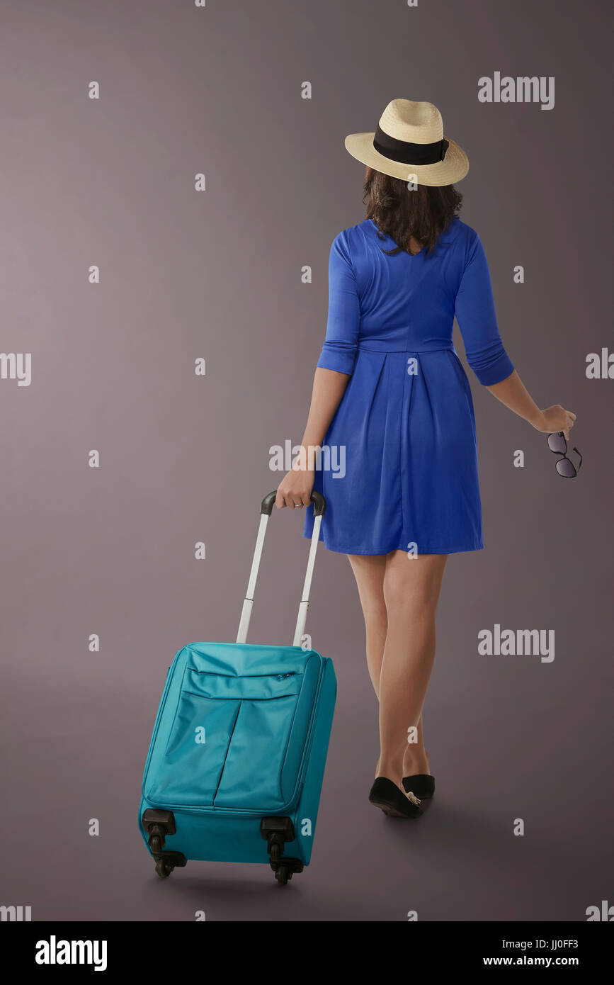 Portrait of asian woman traveling with suitcase over dark background Stock Photo