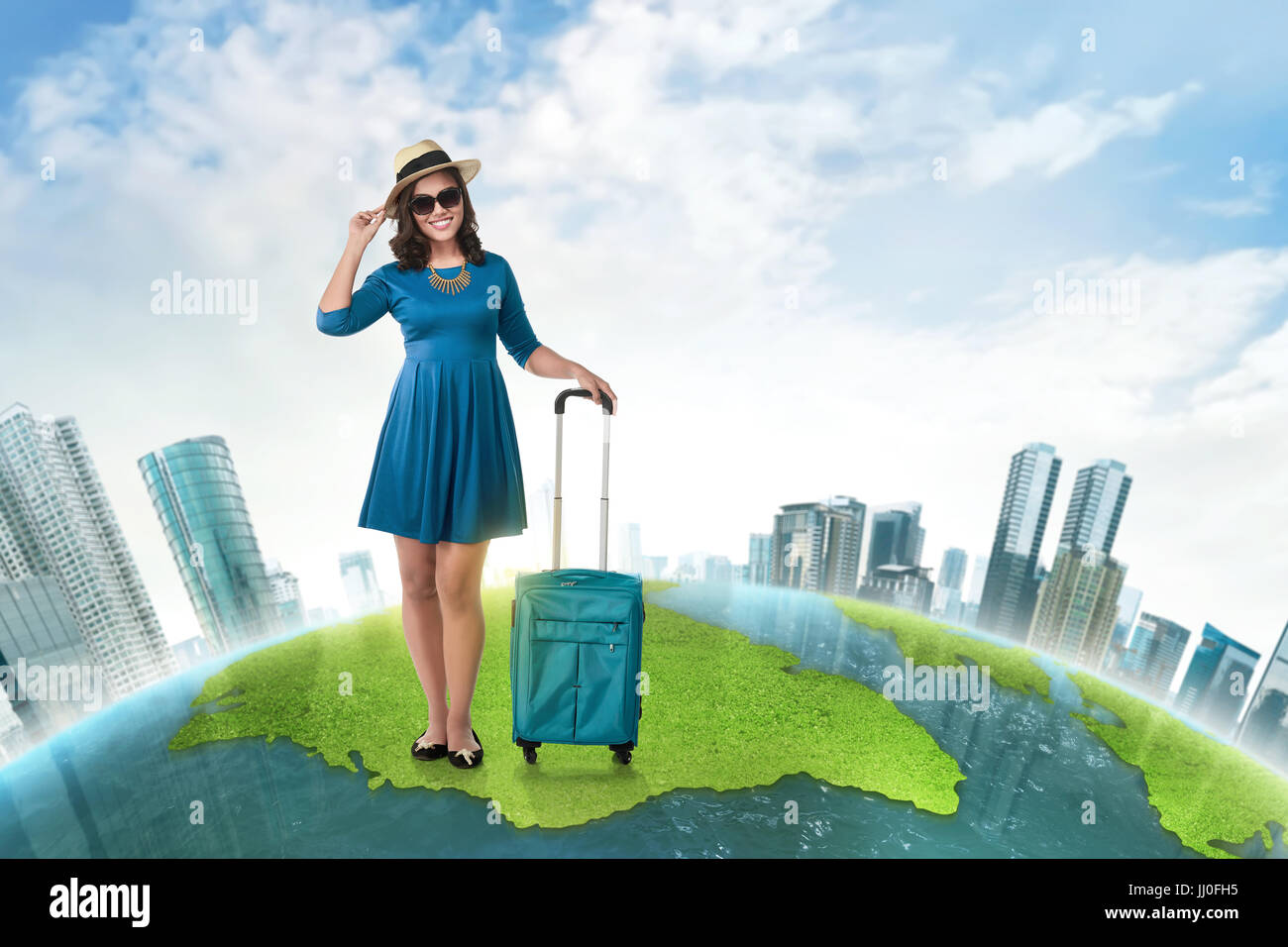 Young asian tourist with suitcase wearing hat standing on the world map Stock Photo