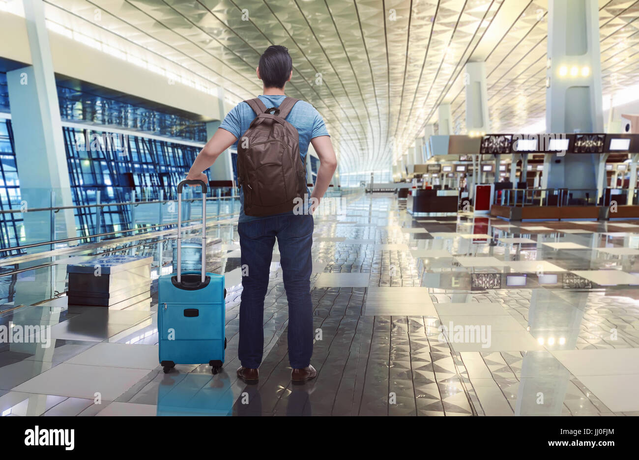 Rear view of asian traveler with backpack and suitcase on the airport Stock Photo