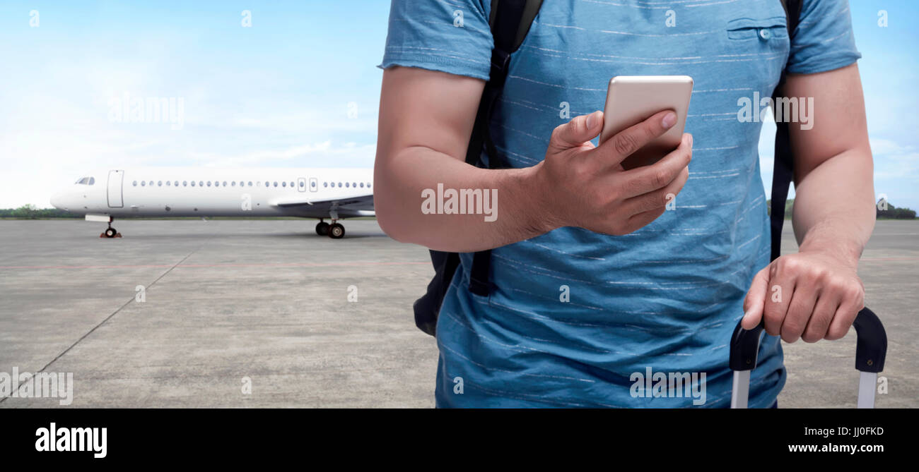 Backpacker asian man carrying bag with phone on his hand on runway airplane Stock Photo