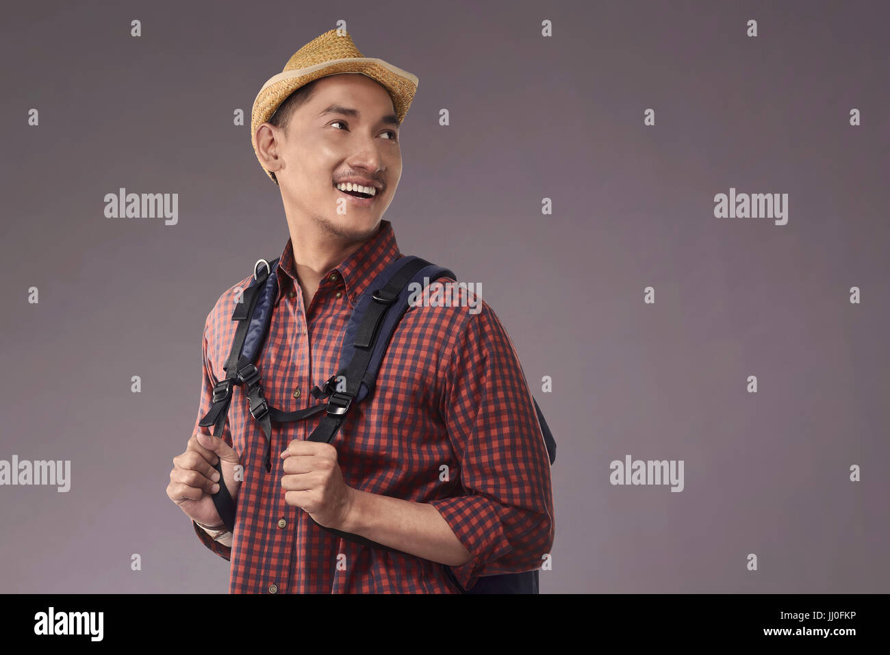 Handsome asian tourist with hat and backpack over dark background Stock Photo
