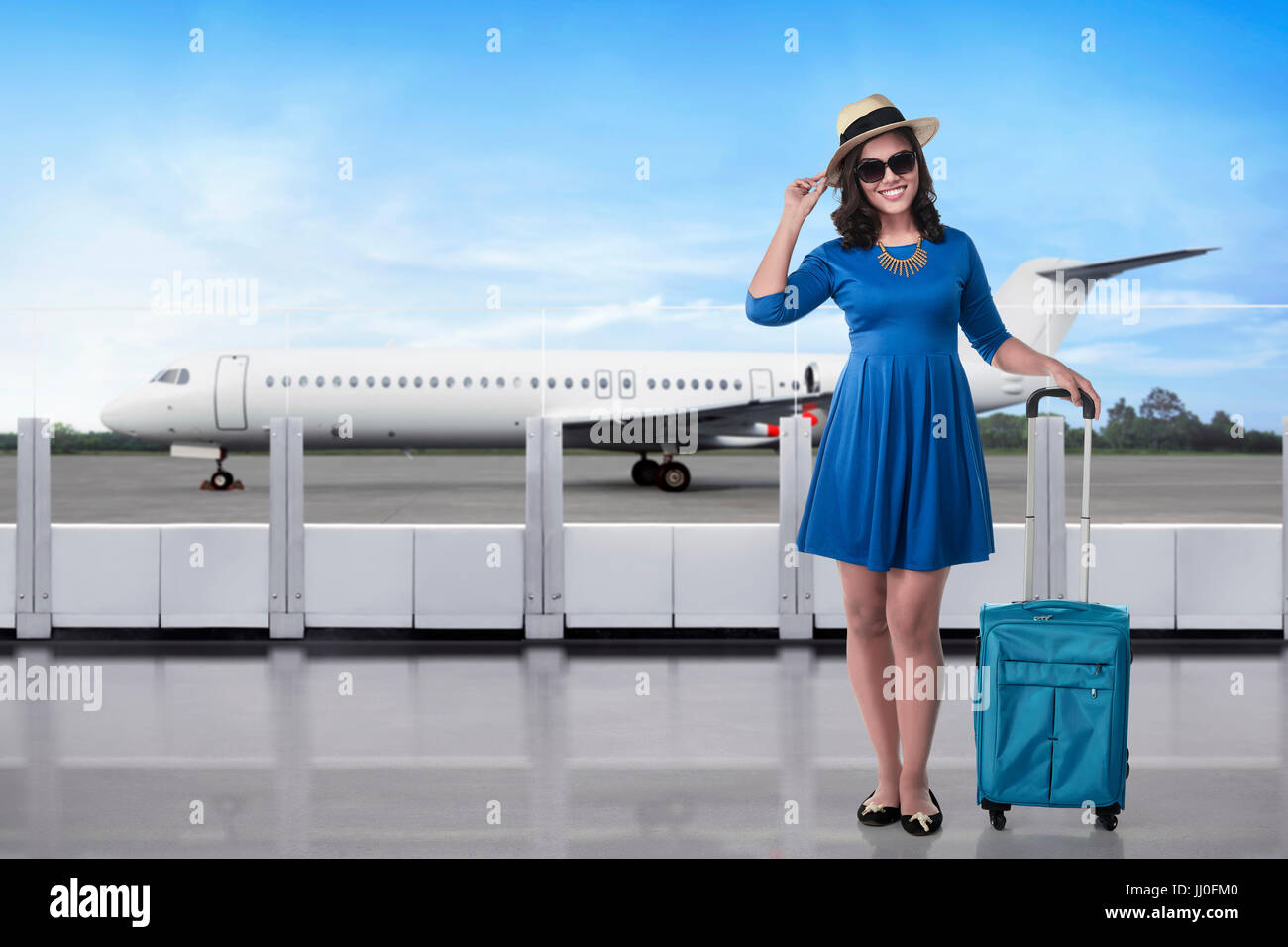 Beautiful asian traveler with hat and suitcase in the airport terminal Stock Photo