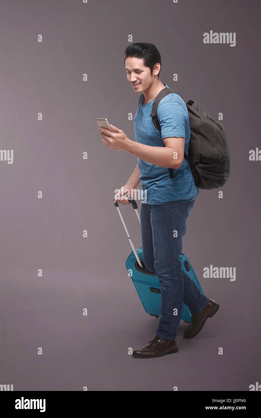 Traveler asian man with backpack using smartphone over dark background Stock Photo