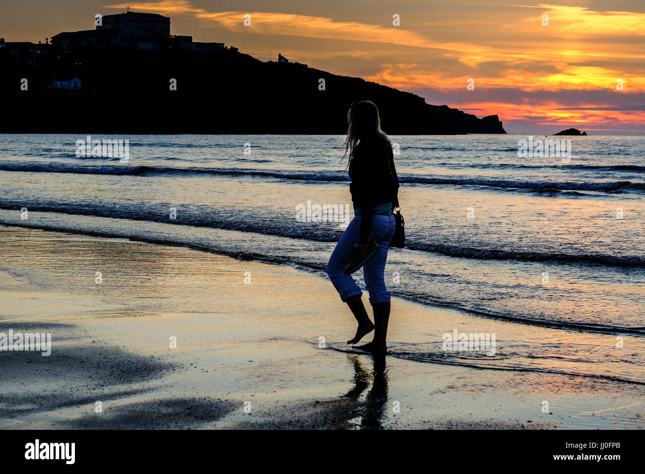 Woman walking along sunset beach hi-res stock photography and images ...