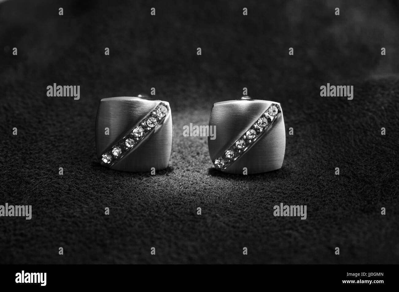 Silver cufflinks with rhinestone on the black matter at the center, of the cufflinks catches the light Stock Photo