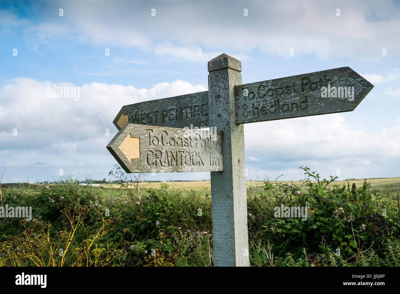 A wooden signpost on a footpath giving directions to West Pentire and Coast Path. Newquay, Cornwall. Stock Photo