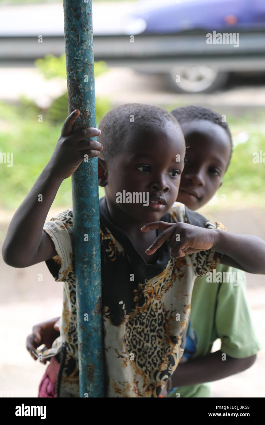 Child hanging themselve at the public restaurant expecting food and assistance from the buyers at the public place in Ivory-Coast's capiltal Abidjan Stock Photo