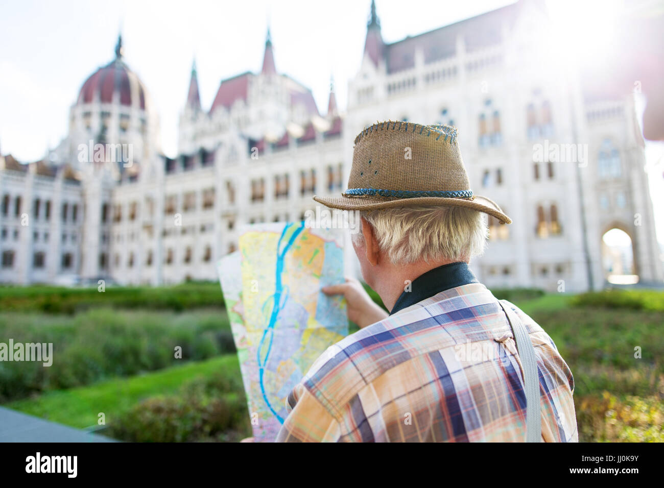 Senior tourist man in hat watching map at Parliament, Budapest, Hungary Stock Photo