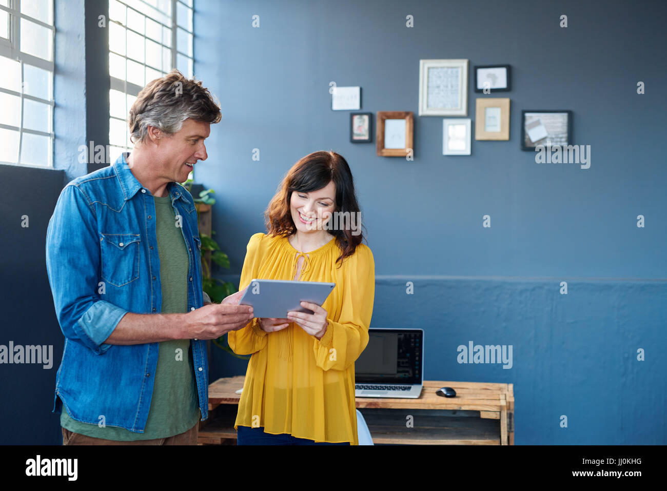 Smiling colleagues talking together over a tablet in an office Stock Photo