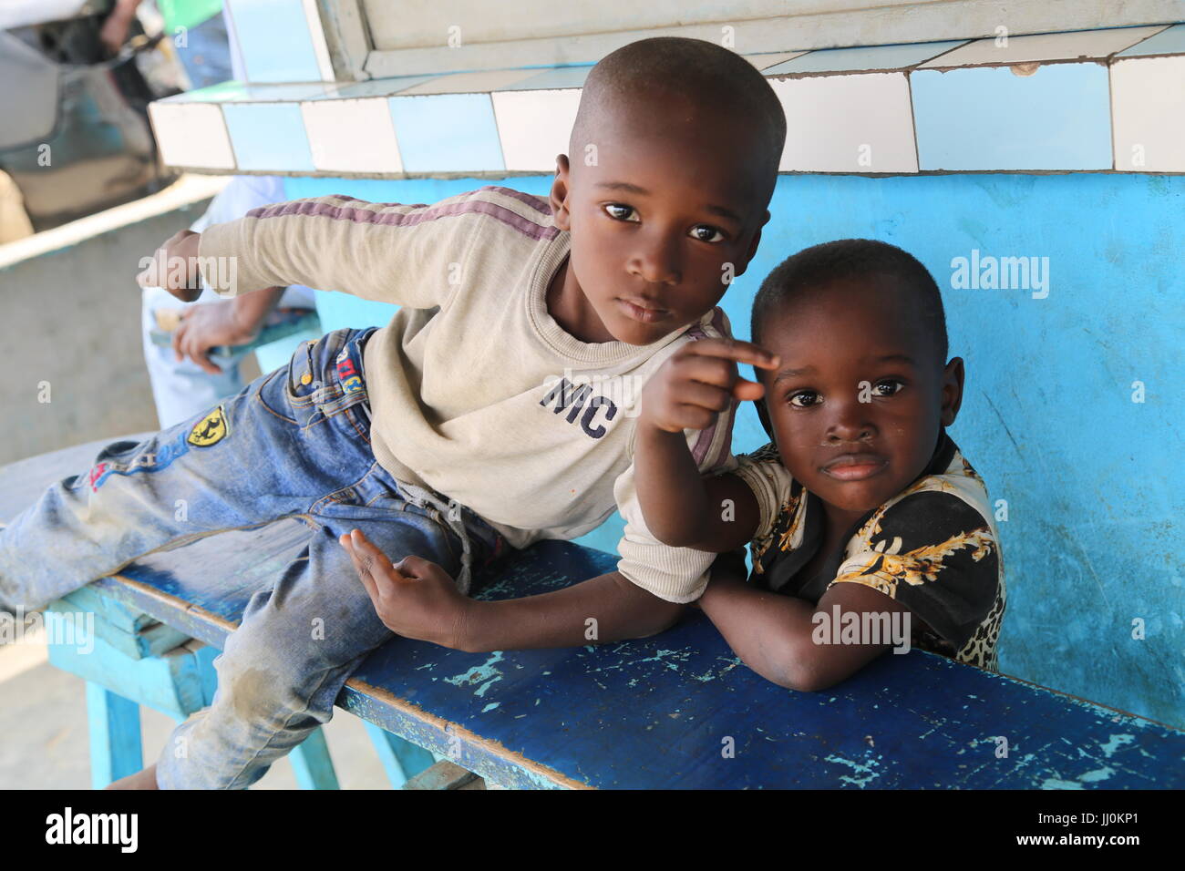 Child hanging themselve at the public restaurant expecting food and assistance from the buyers at the public place in Ivory-Coast's capiltal Abidjan Stock Photo