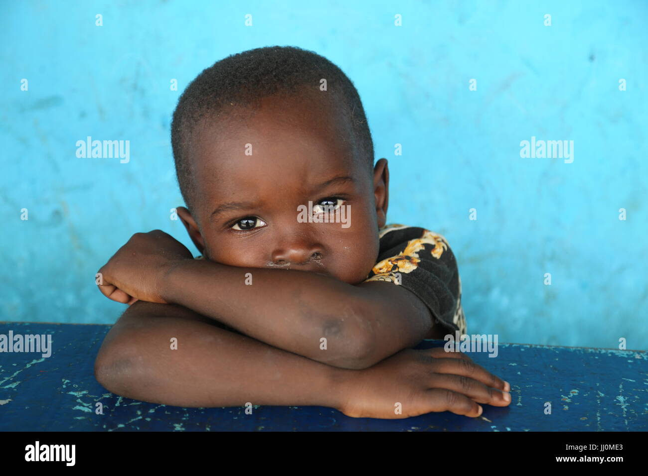 Child hanging themselve at the public restaurant expecting food and assistance from the buyers at the public place in Ivory-Coast's capiltal Abidjan Stock Photo