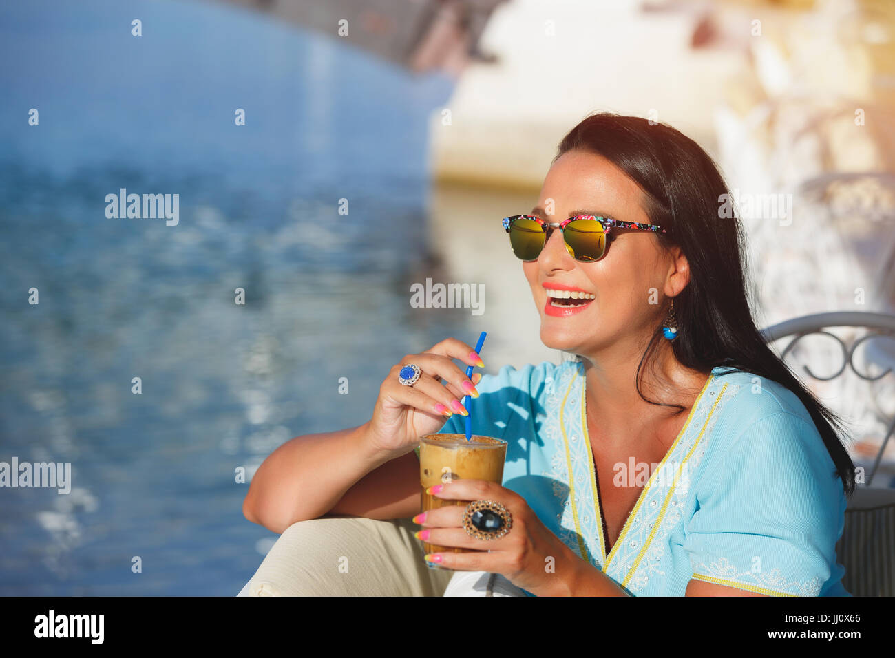 Happy Tanned Woman Drinking Iced Coffee In Seaside Cafe During Sunset Selective Focus Copy Space Happy Tanned Woman Drinking Iced Coffee In Seaside Cafe During Sunset Selective Focus Copy Space