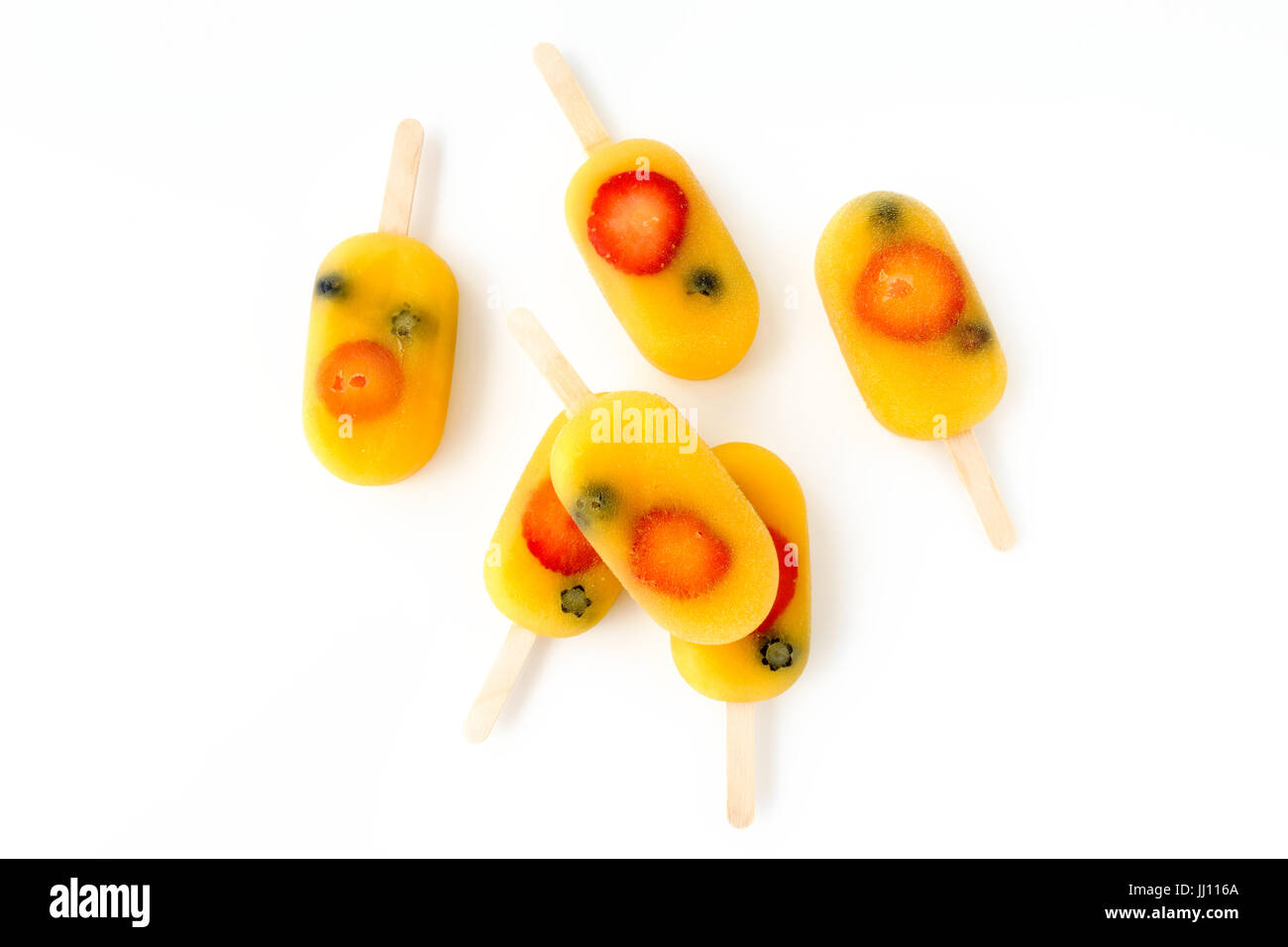 Homemade fruit ice pop, popsicle, ice cream lolly with orange juice, fresh strawberries and blueberries arranged on a white background with copy space Stock Photo