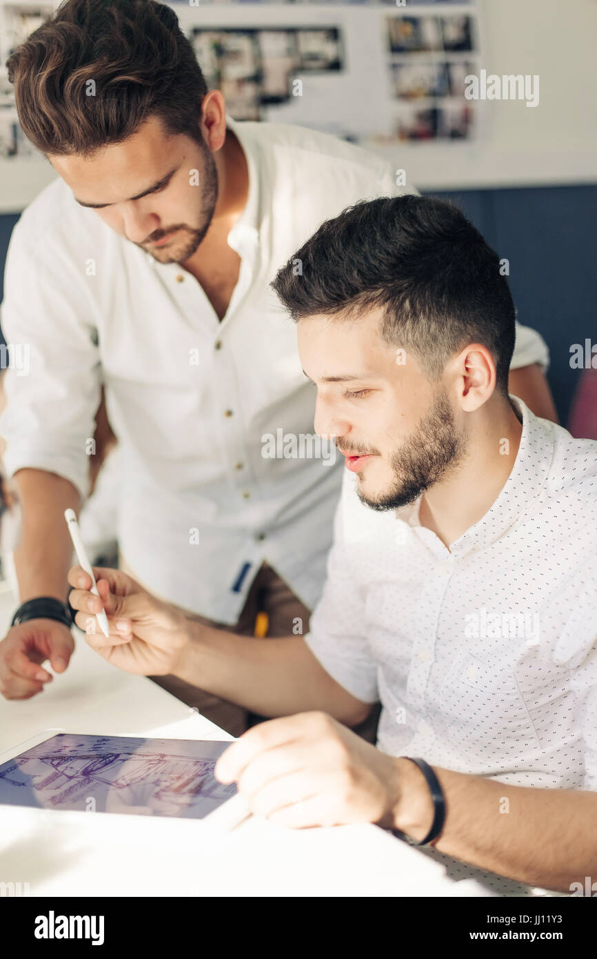 Two man designer drawing sketches and looking at tablet screen Stock ...
