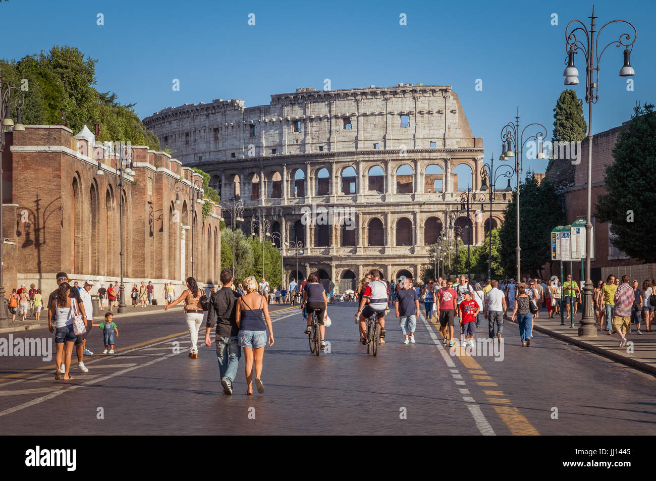 ROME, ITALY - SEPTEMBER 5, 2010: People are walking along the Via dei Fori Imperiali in Rome, enjoying the late afternoon sun. The Colosseum stands ta Stock Photo