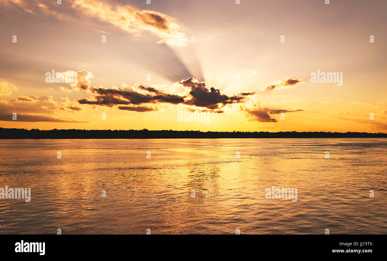 Amazing sunset at Rio Madeira in Porto Velho RO Brazil. Sunset at golden hour with some sunbeams, shadows from clouds and the reflections on the water Stock Photo