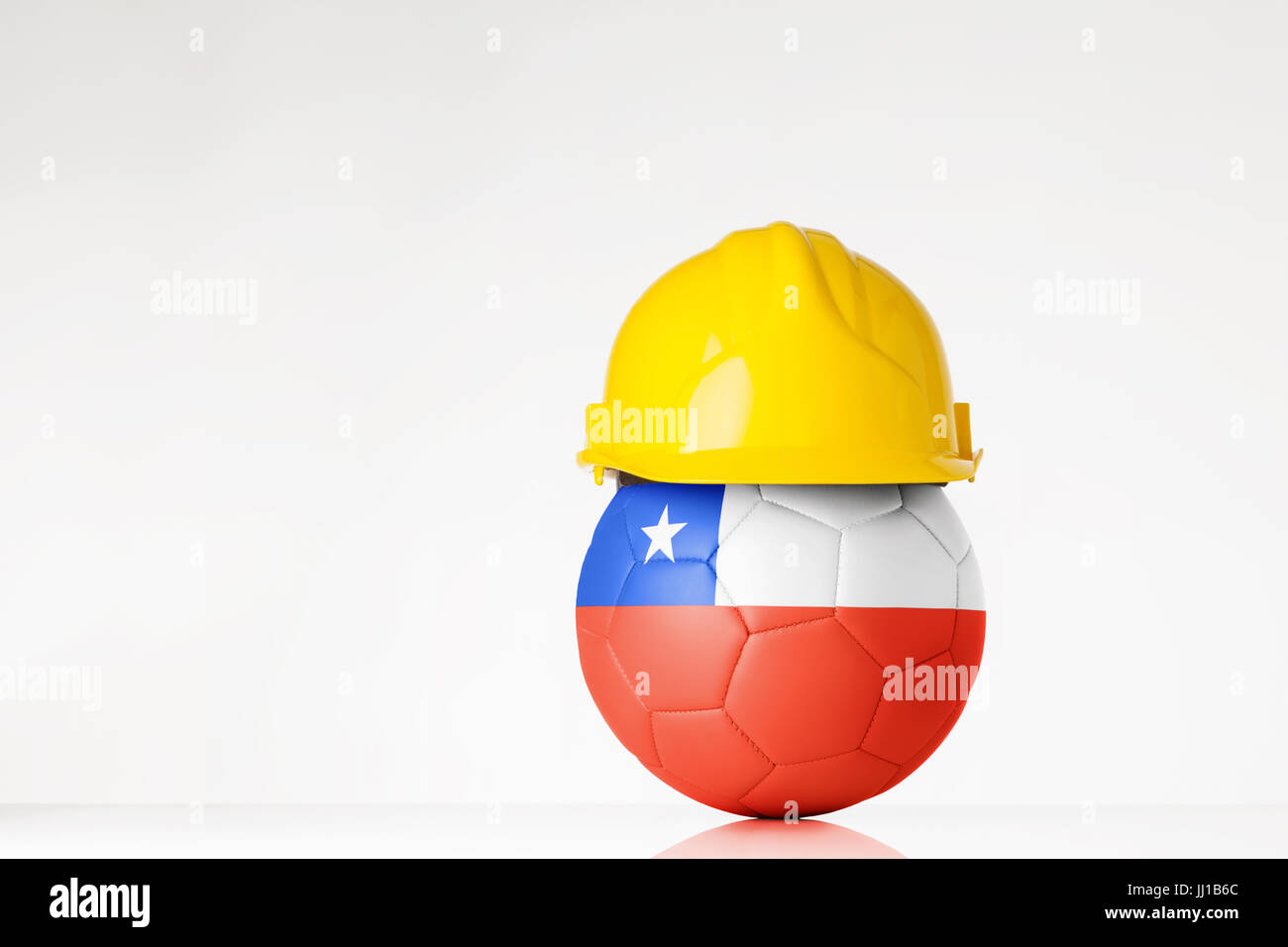 still life image of football wearing a hard hat with the Chile flag  superimposed on the football Stock Photo