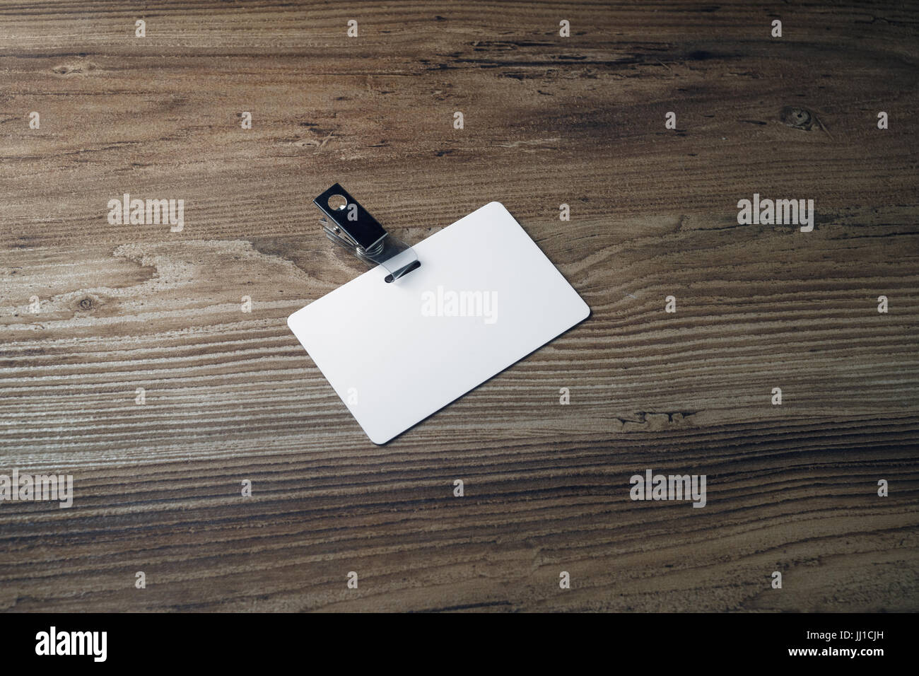 Photo of blank plastic badge on wood background. Template for ID ...