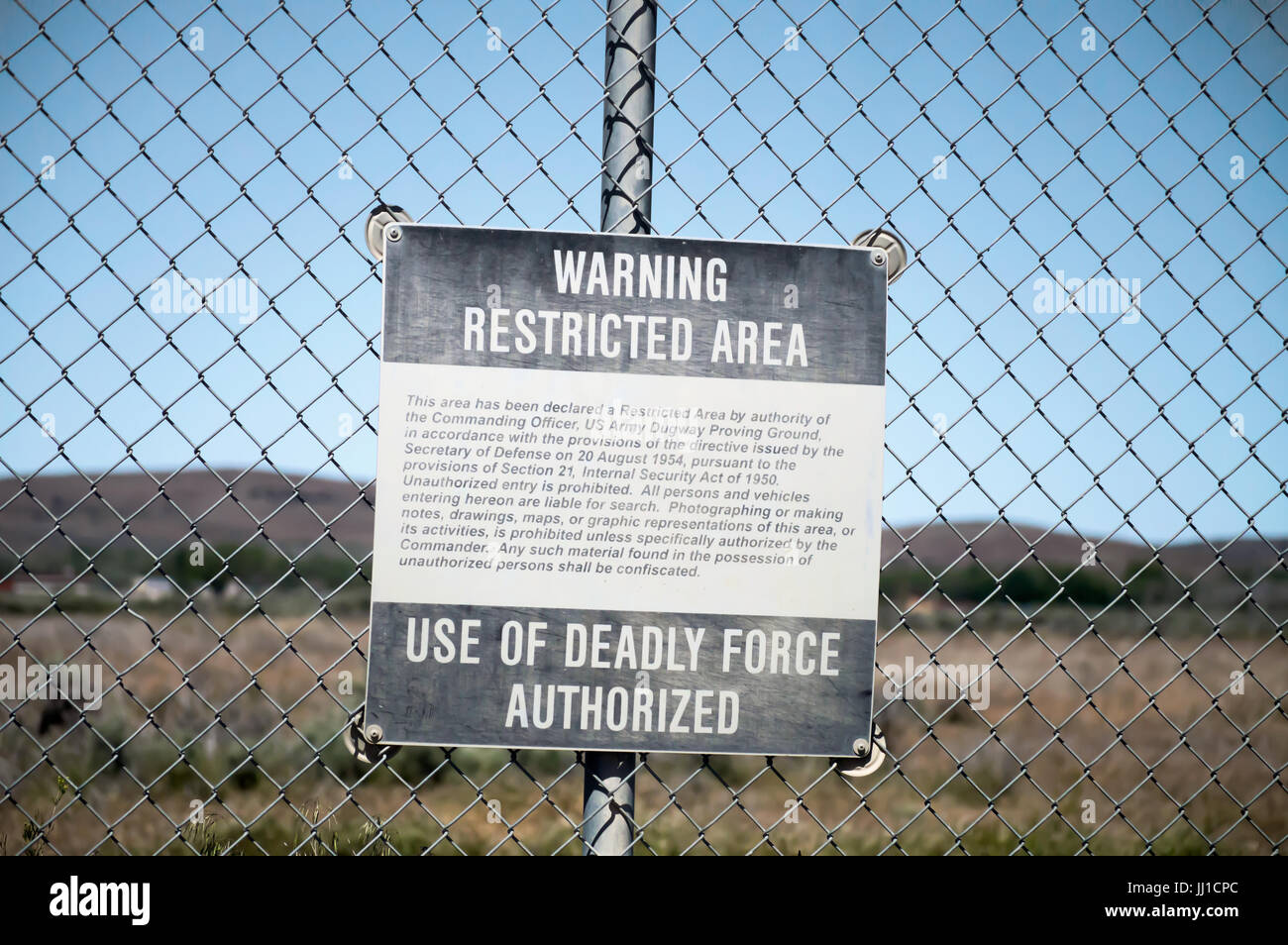 Warning Restricted Area sign, Deadly force authorized sign hung on a chain link fence. Stock Photo