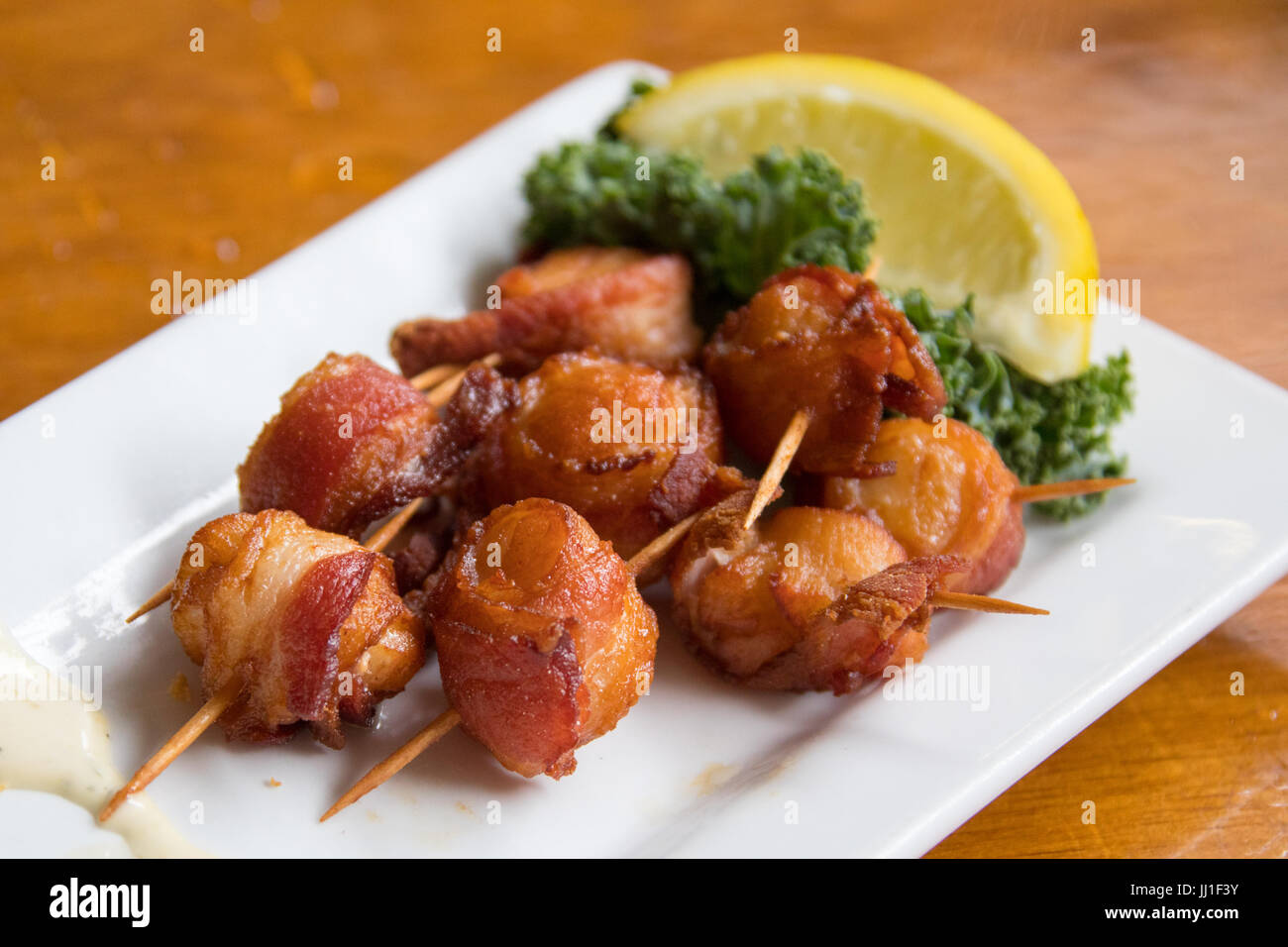 Locally sourced scallops wrapped in bacon at The Nantucket Lobster Trap Restaurant, Nantucket, MA, USA Stock Photo