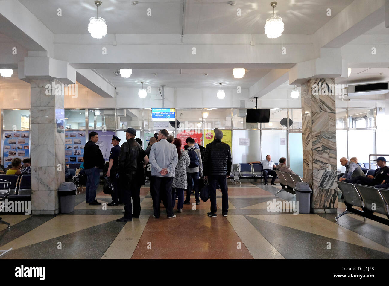 Passengers wait for their flight at the departure hall of Yuzhno-Sakhalinsk Airport also called Khomutovo in the city of Yuzhno-Sakhalinsk, in the island of Sakhalin, in the Pacific Ocean. Russia Stock Photo
