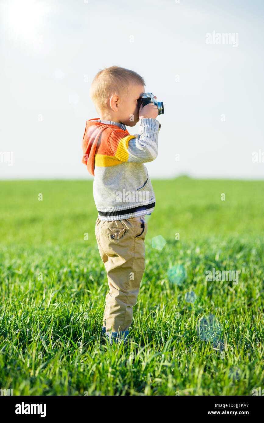 Little boy with an old camera shooting outdoor. Stock Photo