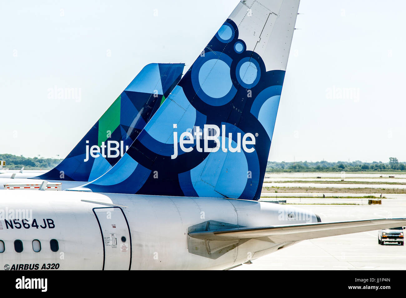 Two JetBlue airplanes are parked by the gates awaiting passenger boarding. Stock Photo