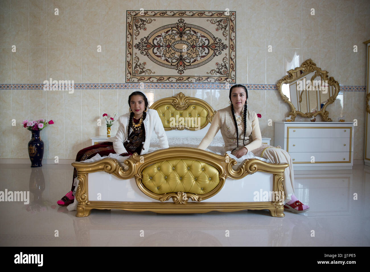 Girls of a wealthy Roma gypsy family posing in the luxurious bedroom of their house, Ivanesti, Romania Stock Photo