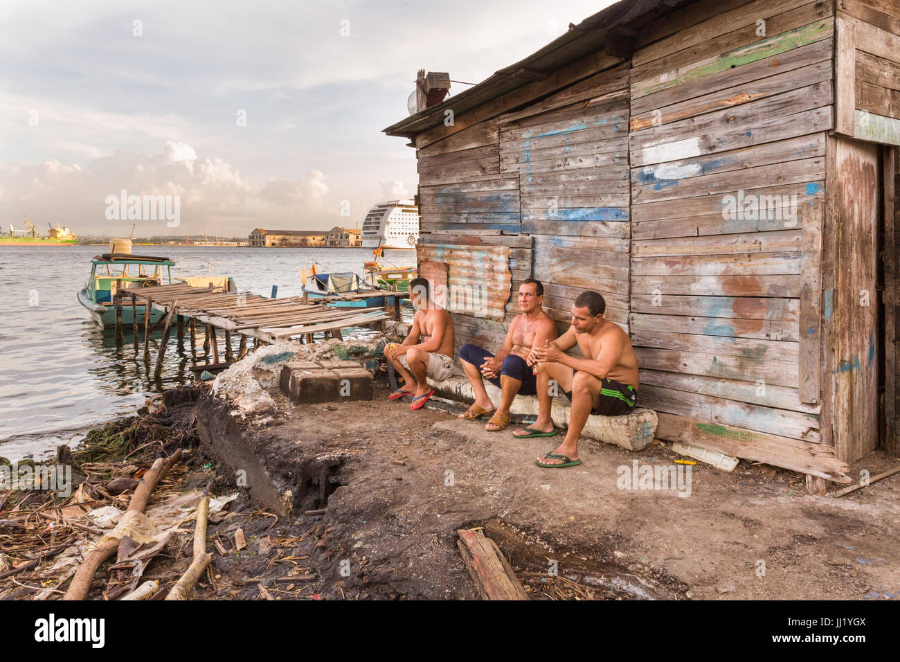 Fishermen rest against a shed in Casa Blanca, or Casablanca, urban fishing harbour, Havana, Cuba Stock Photo