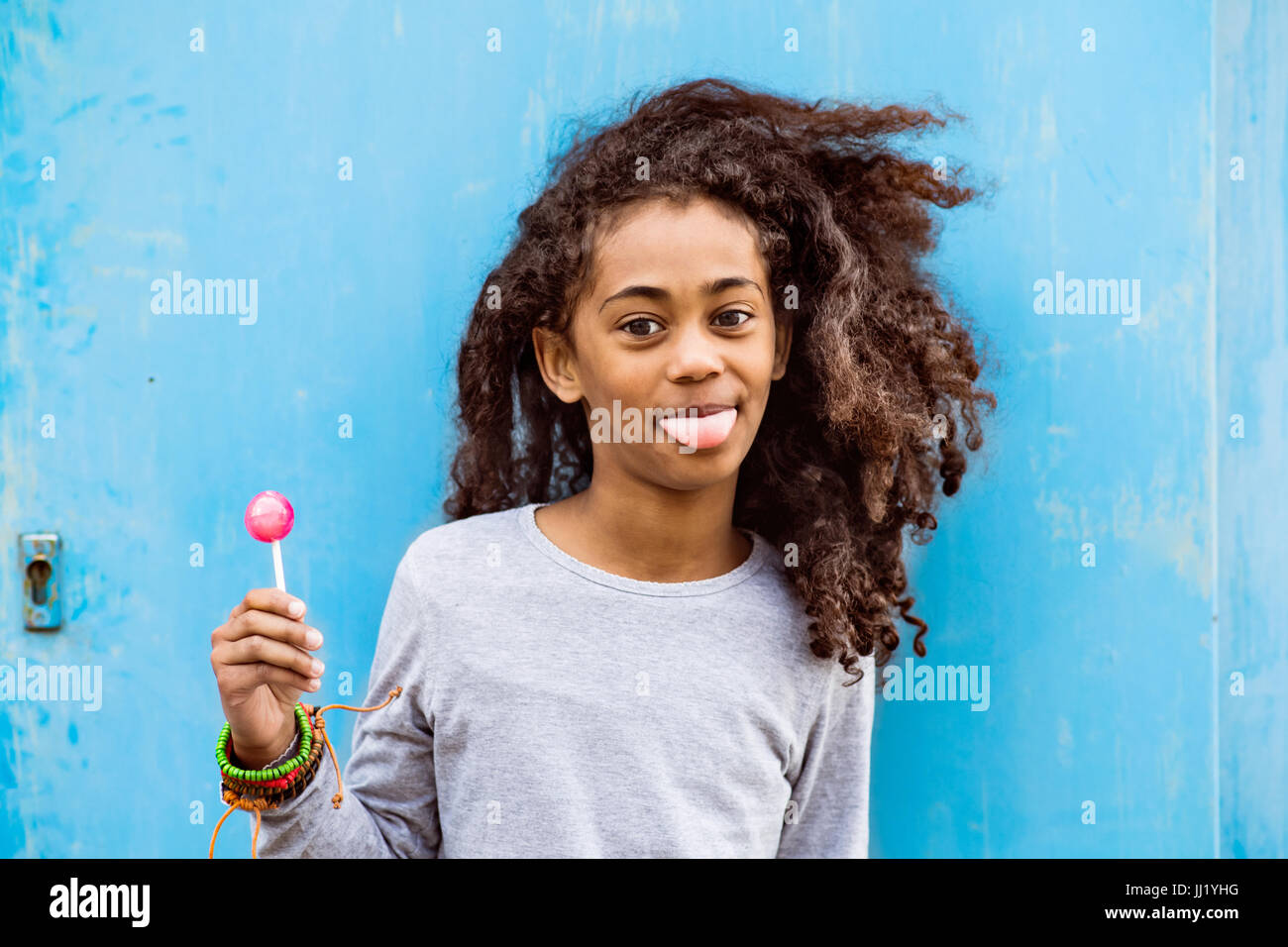 African american girl with curly hair outdoors eating lollipop. Stock Photo