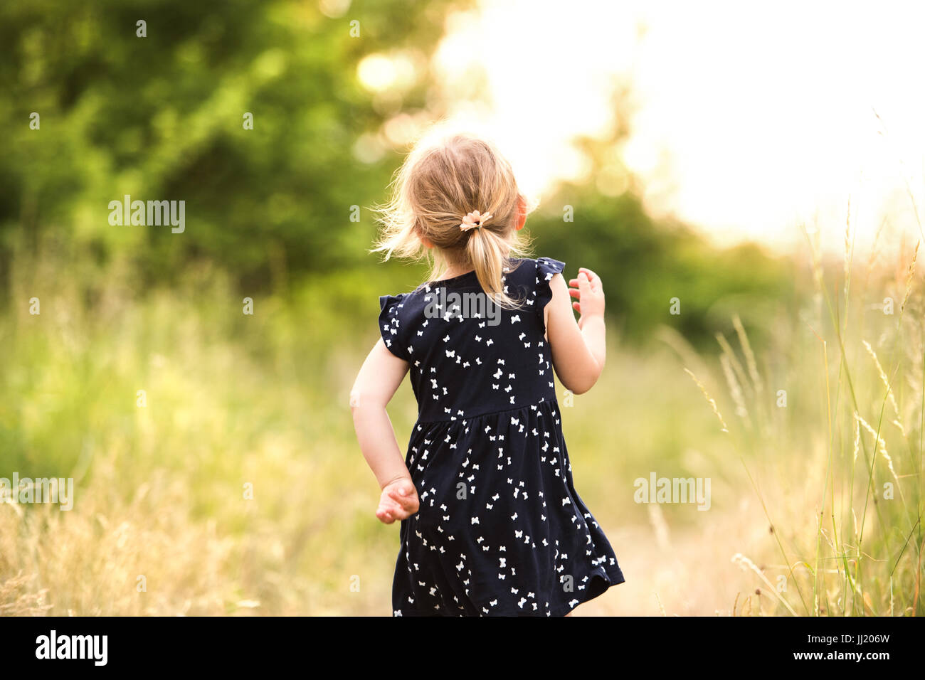 Cute little girl outside in in green sunny summer nature. Stock Photo
