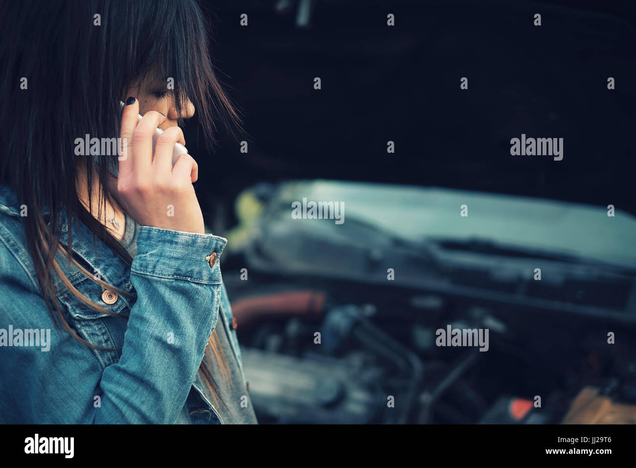 Young Caucasian Woman With Brown Hair Under The Hood Of Her Car