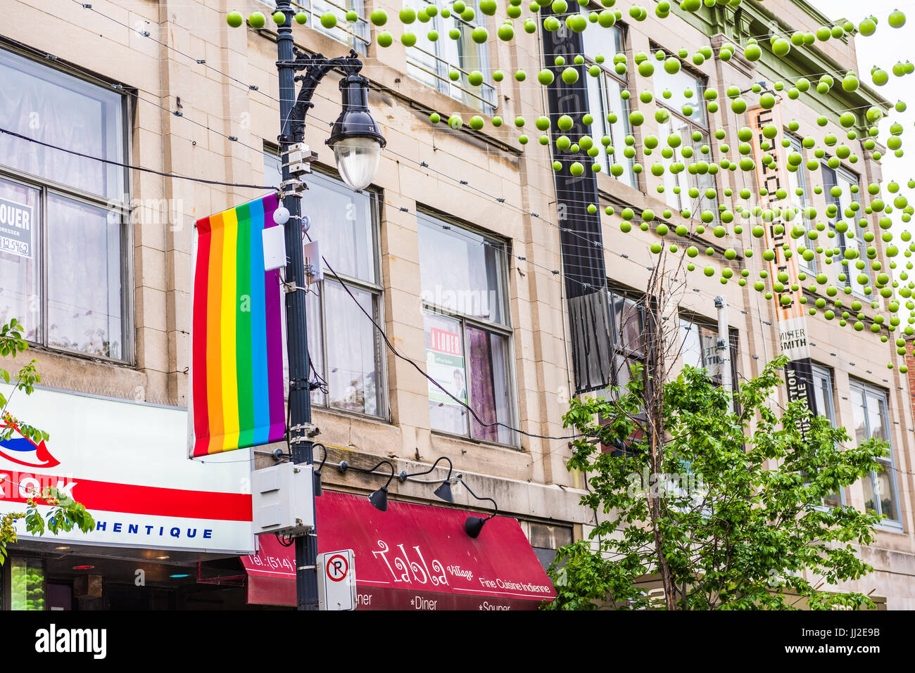 Montreal, Canada - May 26, 2017: Sainte Catherine street in Montreal's Gay Village in Quebec region with green hanging decorations and lgbt flag Stock Photo