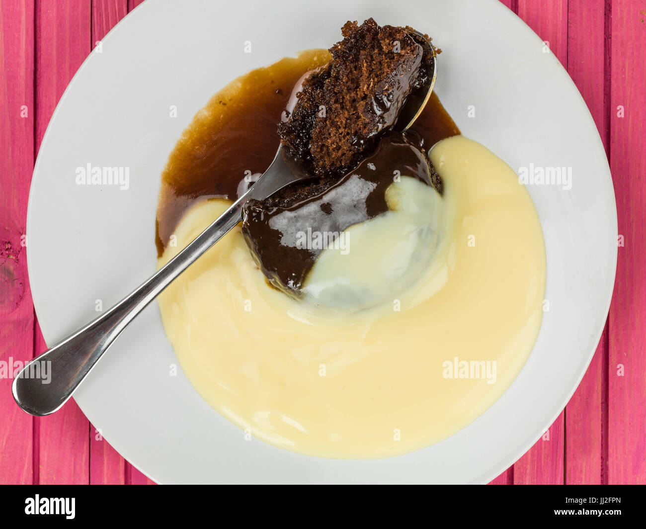 Sticky Toffee Pudding Dessert Served With Hot Custard Against a Pink