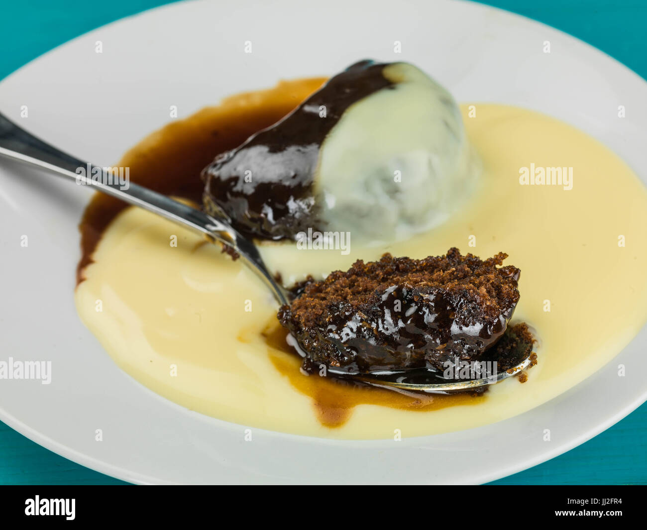 Sticky Toffee Pudding Dessert Served With Hot Custard Against a White
