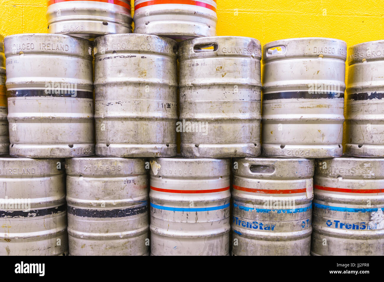 Aluminium beer kegs stacked up against a painted orange wall at an Irish pub. Stock Photo
