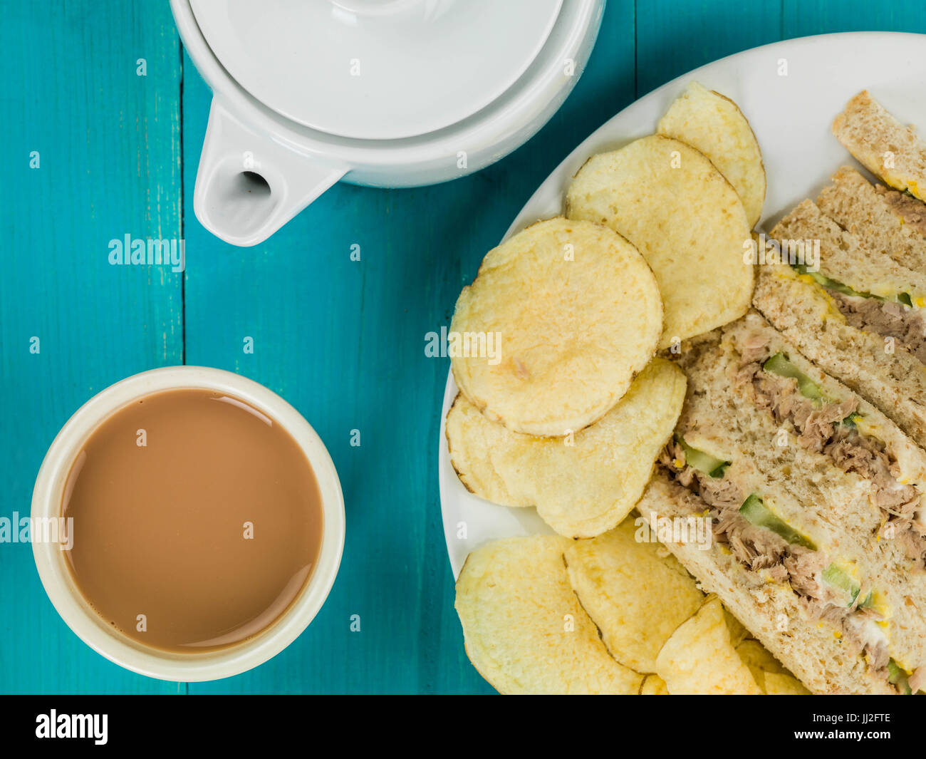 Tuna Sweetcorn and Cucumber Oatmeal Bread Sandwich With Potato Crisps Against a Blue Wooden Background Stock Photo
