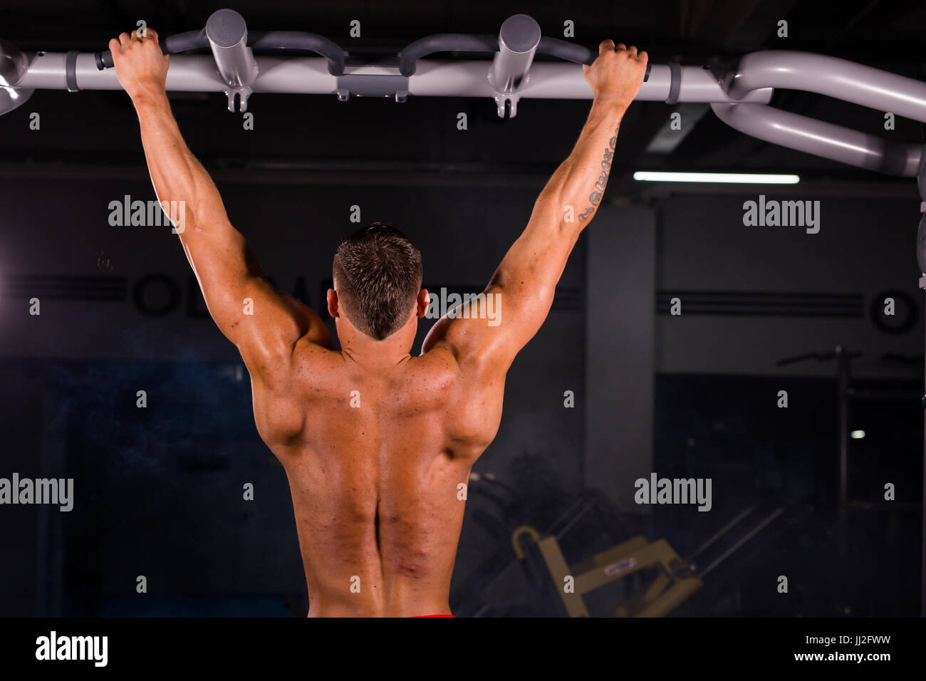 Rear view of muscular man doing pull ups at the gym Stock Photo - Alamy