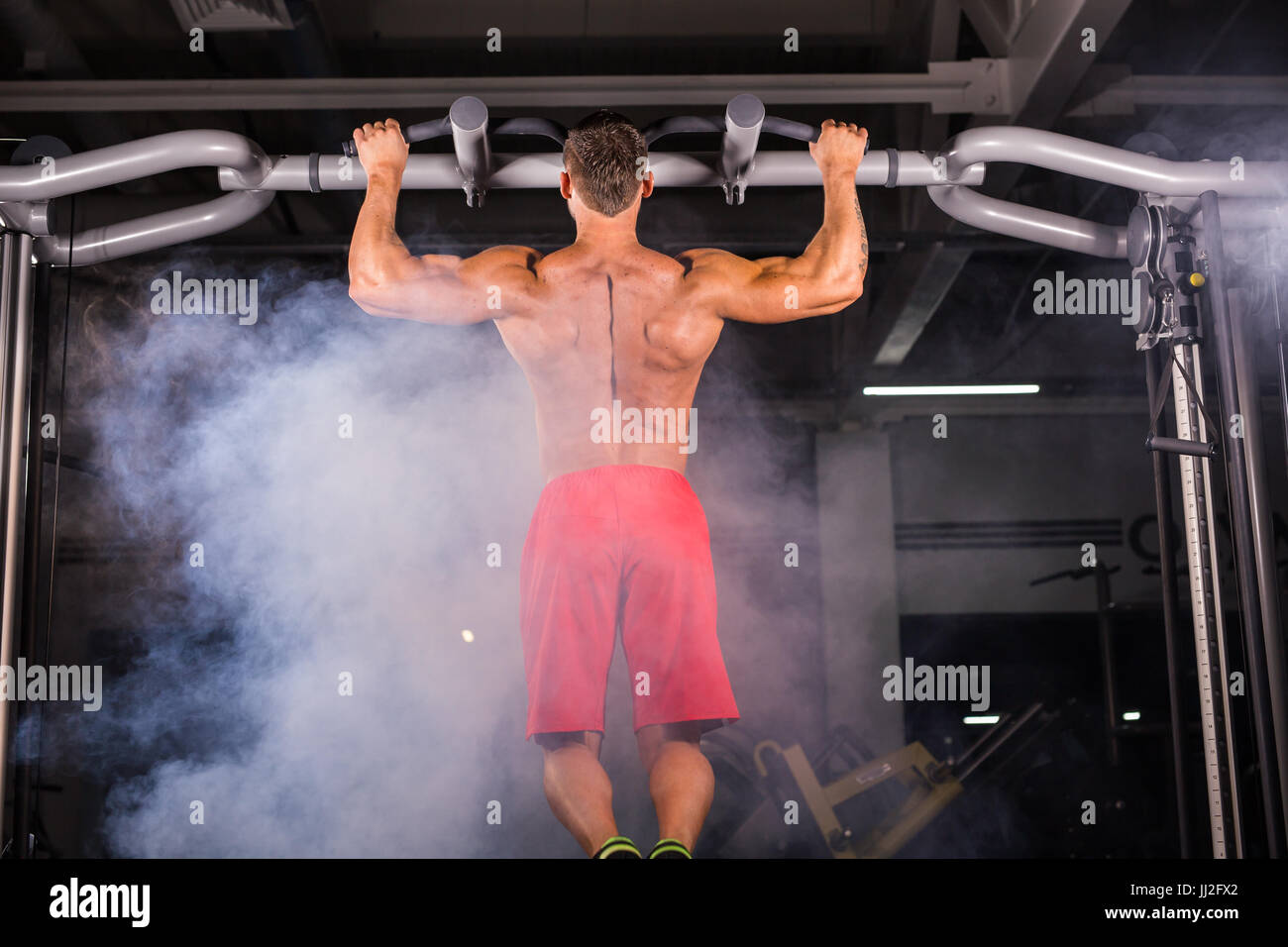 Rear view of muscular man doing pull ups at the gym Stock Photo - Alamy
