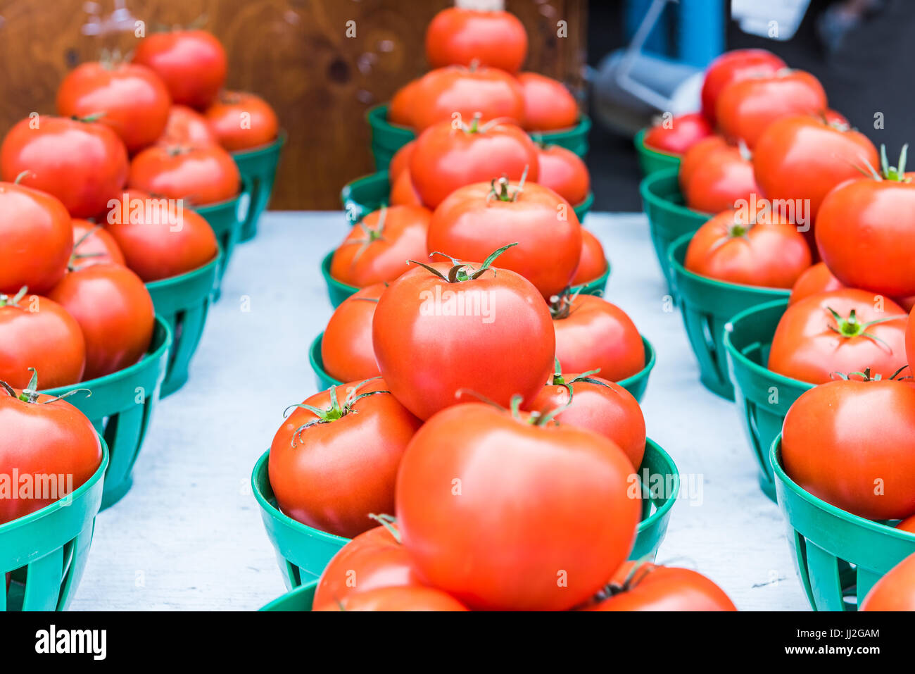 Closeup of red ripe tomatoes with green stems in baskets in farmers market Stock Photo