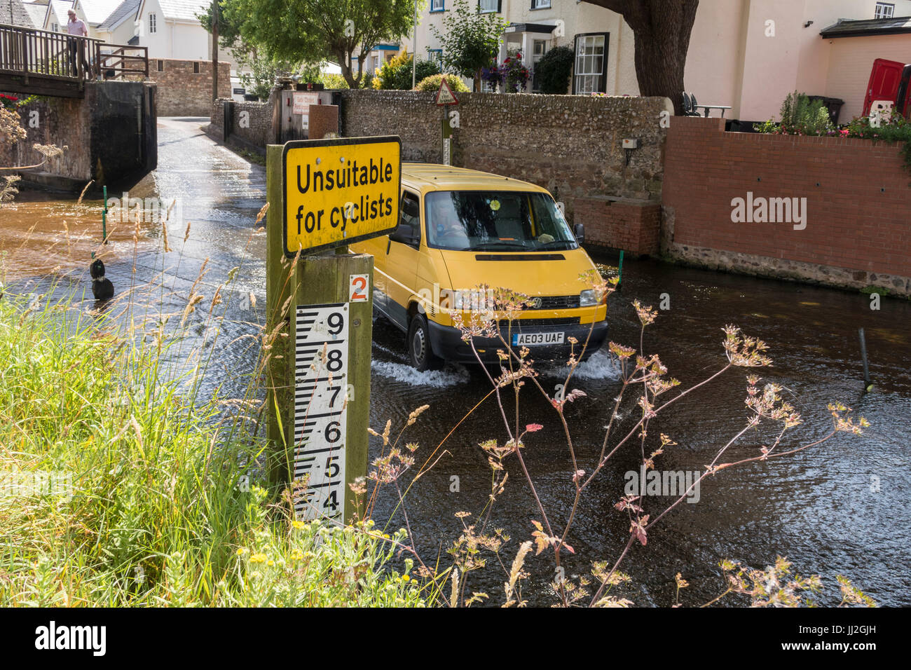 Sign saying 'unsuitable for cyclists' at the ford across the river Sid at Sidmouth, Devon, with a van crossing the river. Stock Photo