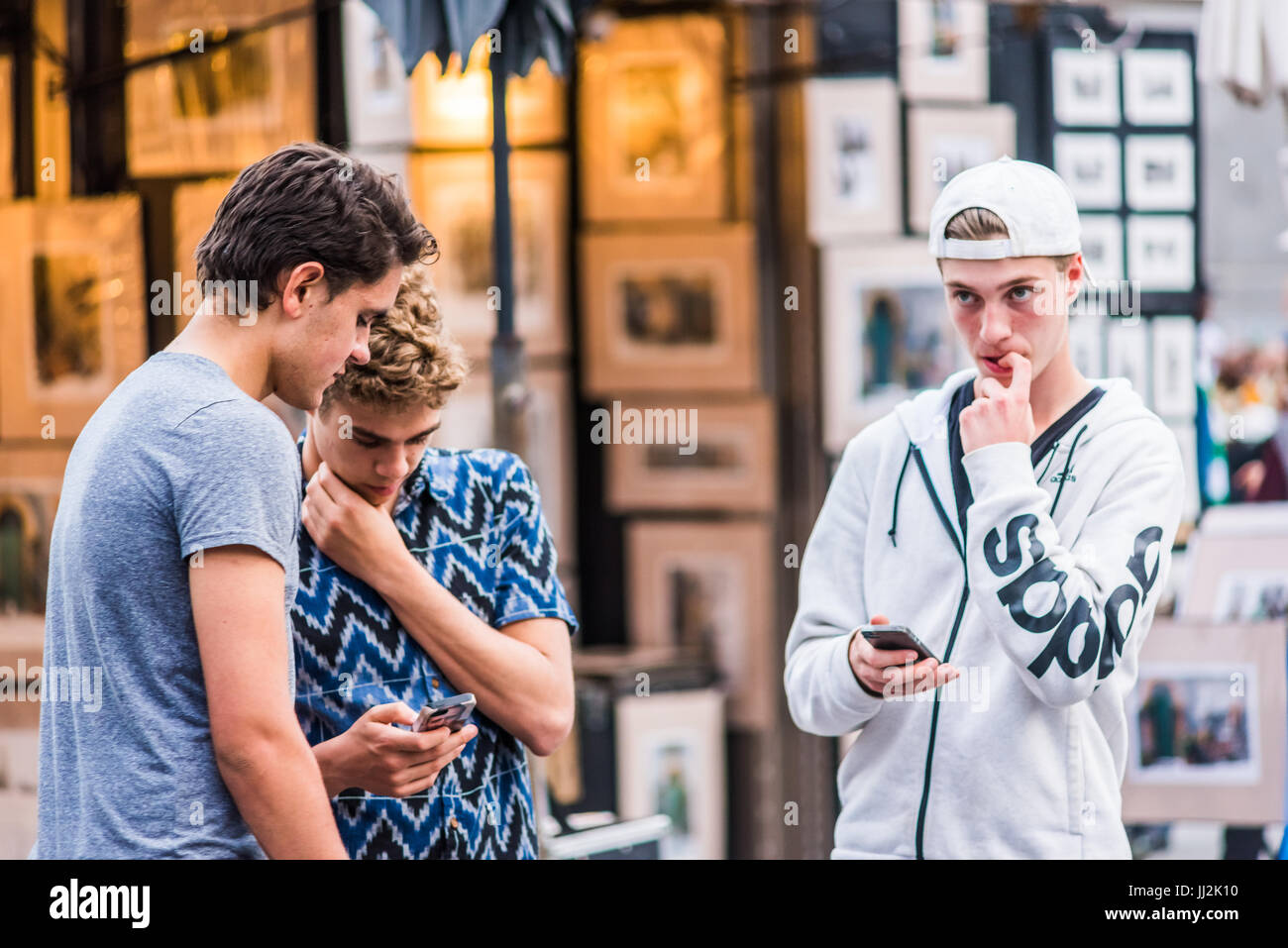 Montreal, Canada - May 27, 2017: Old town area with young boys looking at their smartphones in evening in Quebec region city Stock Photo