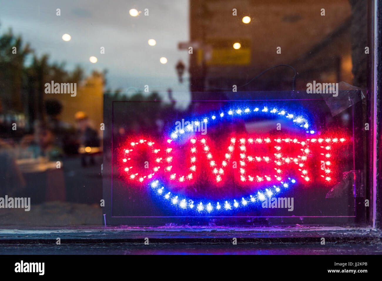 French ouvert open sign for store shop or restaurant glowing in the evening with window reflection Stock Photo