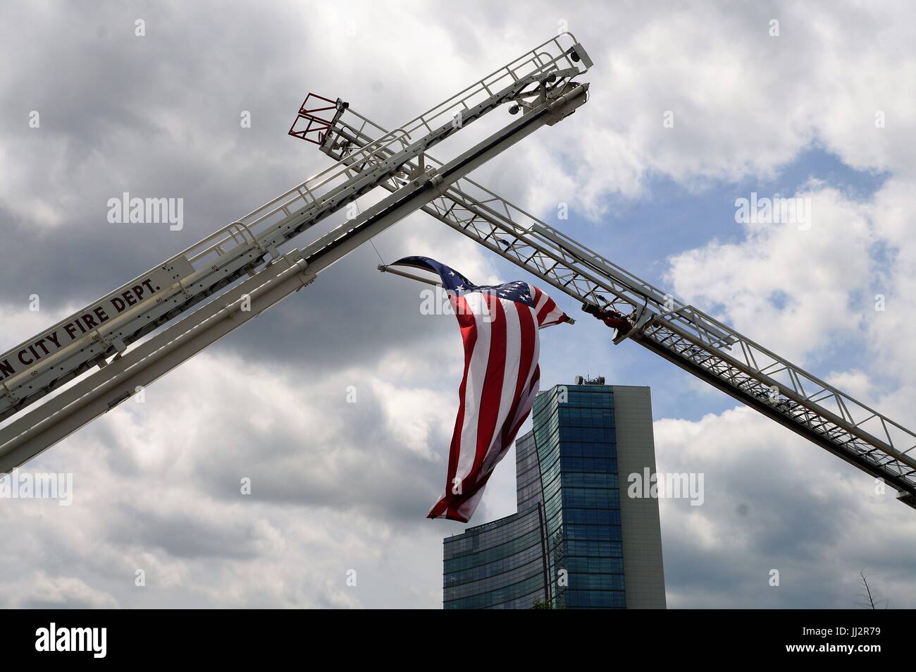American flag suspended from fire trucks waving in blue sky Stock Photo