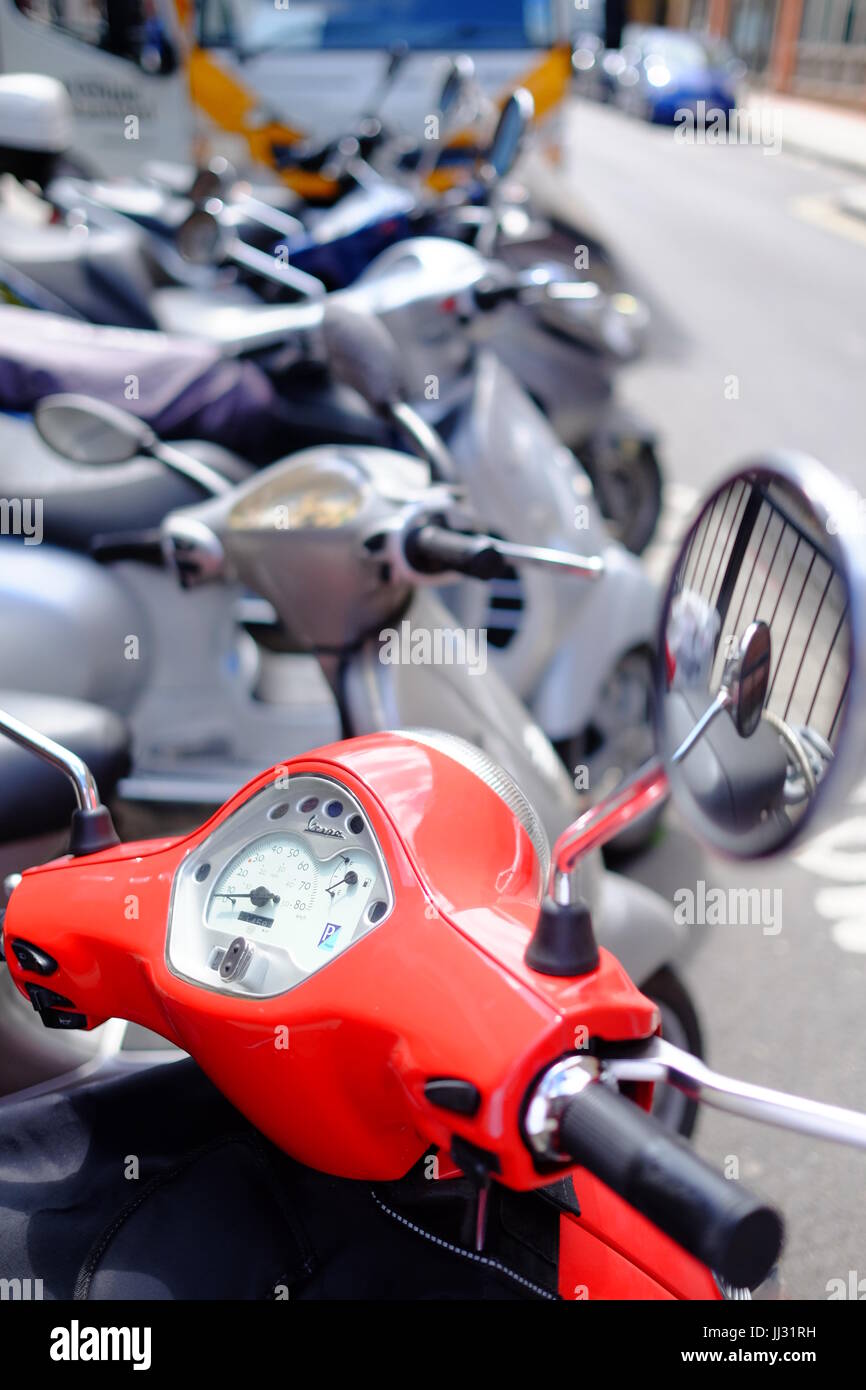 A red Vespa scooter parked in a row of scooters near Euston station, London Stock Photo